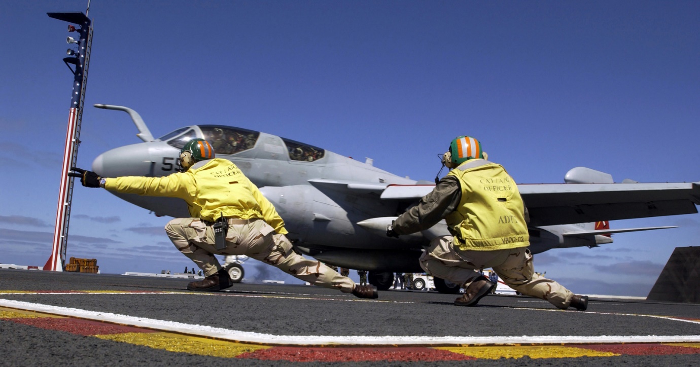 US Navy (USN) (yellow shirt) Aircraft Handling Officers launch a EA-6B  Prowler aircraft assigned to
